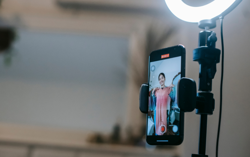 Content creator recording Amazon product videos with a smartphone and ring light, showcasing a dress for an online audience.